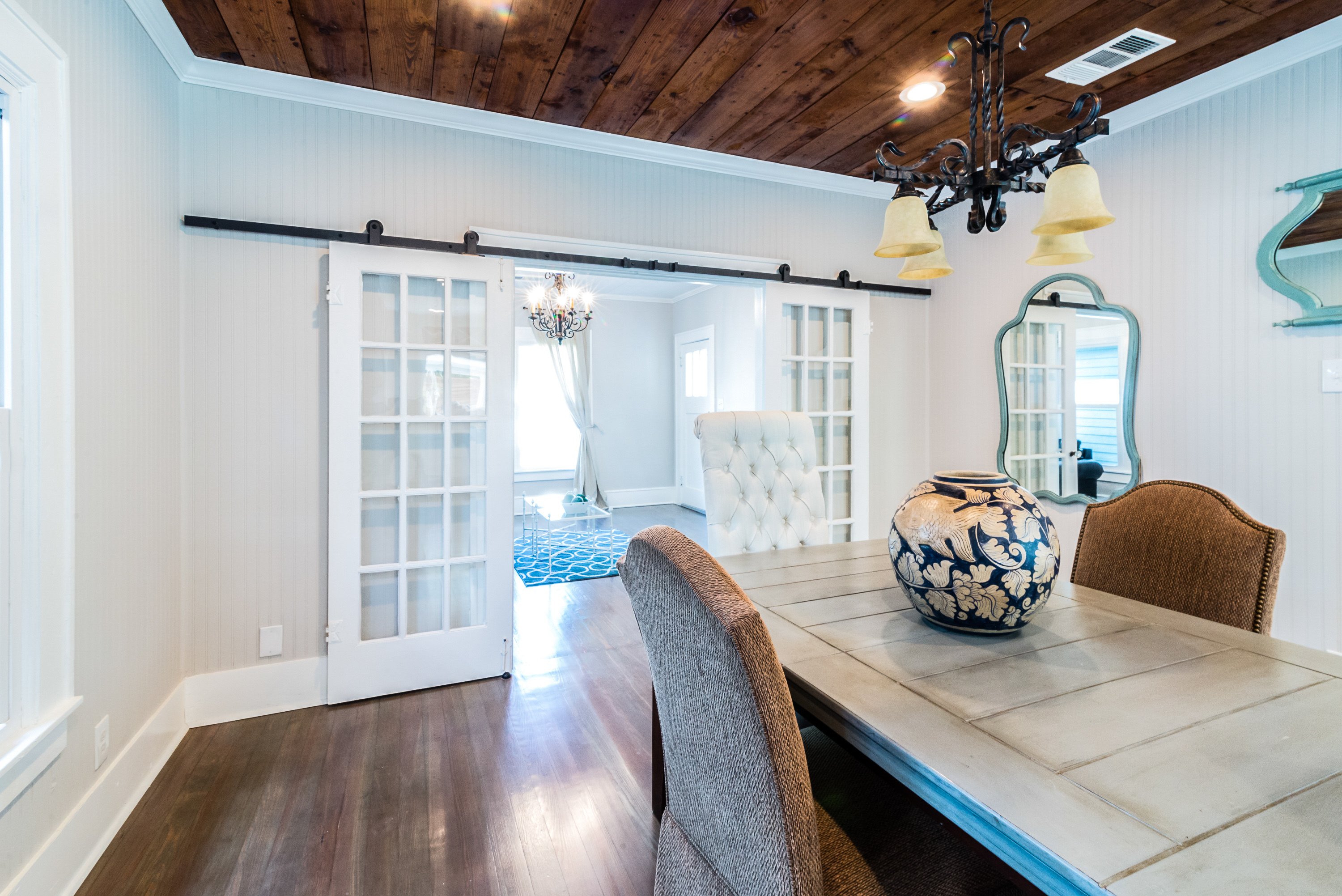 Dining room with sliding French doors, wood shiplap ceiling, and farmhouse style dining table